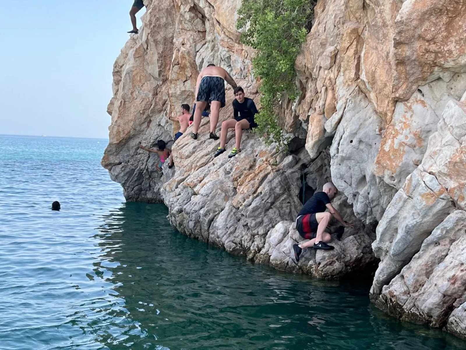The dhow anchored in a cove, swimmers in the water
